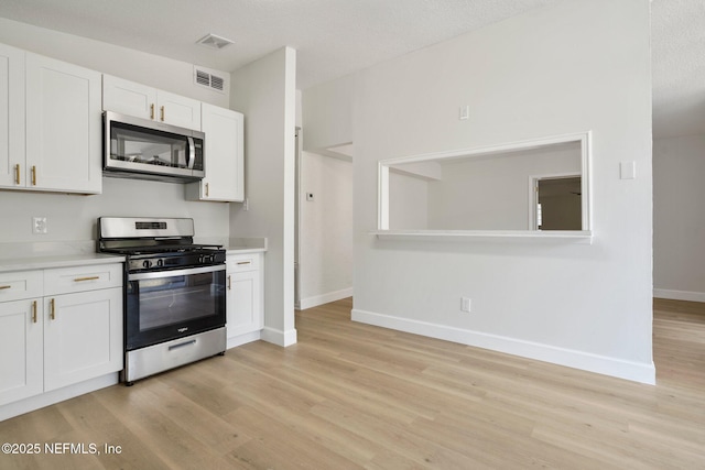 kitchen featuring white cabinetry, stainless steel appliances, and light hardwood / wood-style floors