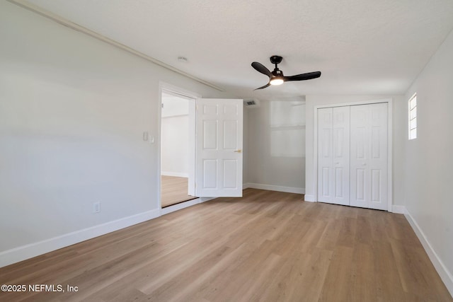 unfurnished bedroom featuring ceiling fan, a textured ceiling, light wood-type flooring, and a closet