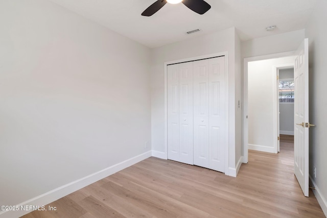 unfurnished bedroom featuring ceiling fan, a closet, and light wood-type flooring