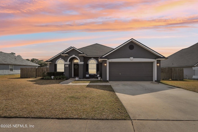 single story home featuring stucco siding, a front lawn, fence, concrete driveway, and a garage