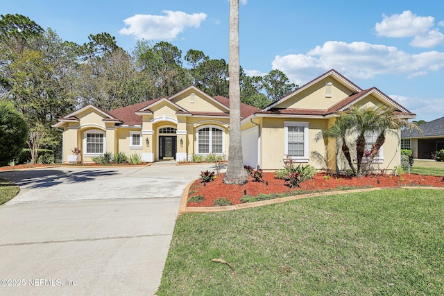 mediterranean / spanish-style home with stucco siding, concrete driveway, and a front lawn