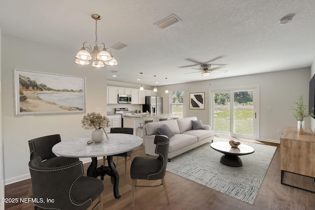 dining area featuring ceiling fan with notable chandelier, hardwood / wood-style floors, and a textured ceiling