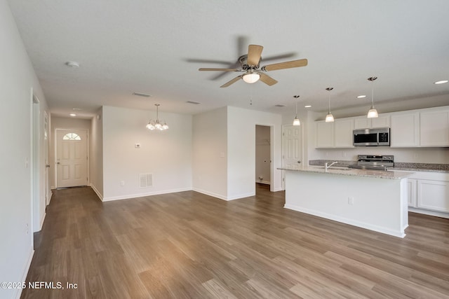 kitchen with stainless steel appliances, decorative light fixtures, an island with sink, and white cabinets