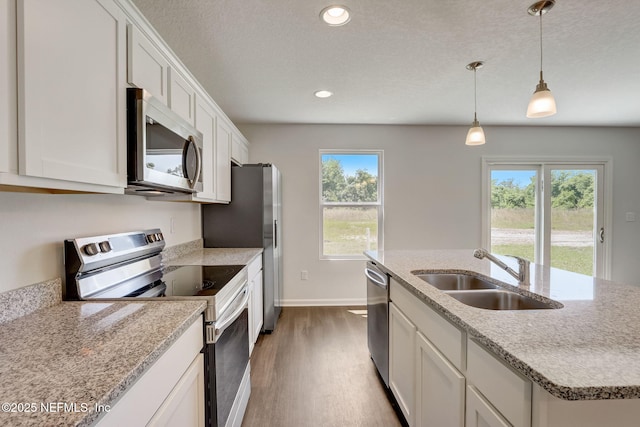 kitchen with sink, white cabinetry, a center island with sink, appliances with stainless steel finishes, and pendant lighting