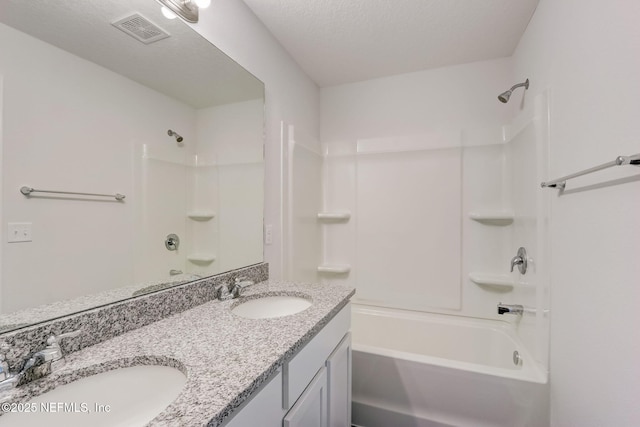 bathroom with vanity, tub / shower combination, and a textured ceiling