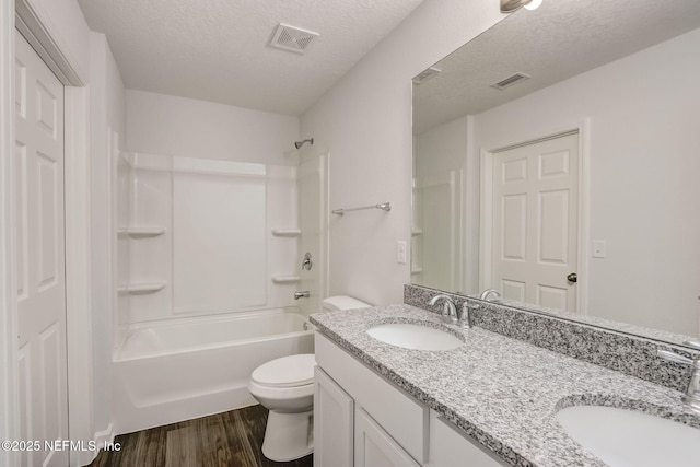 full bathroom with washtub / shower combination, toilet, a textured ceiling, vanity, and hardwood / wood-style floors