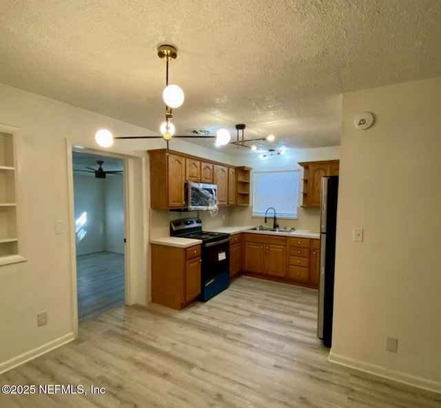 kitchen featuring pendant lighting, sink, stainless steel appliances, a textured ceiling, and light hardwood / wood-style flooring