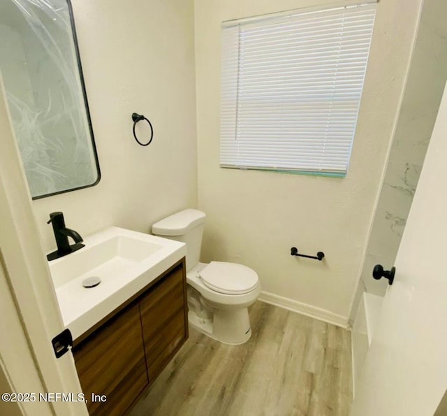 bathroom featuring wood-type flooring, toilet, and vanity