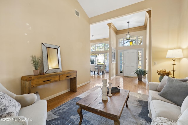 living room featuring crown molding, high vaulted ceiling, and light hardwood / wood-style floors