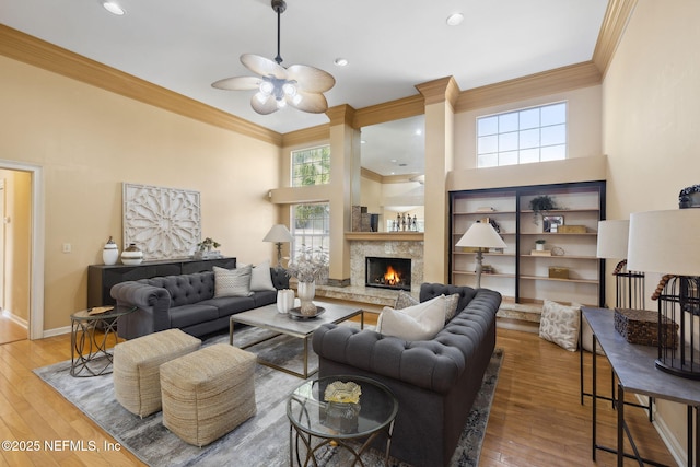 living room with a high ceiling, wood-type flooring, ceiling fan, and crown molding