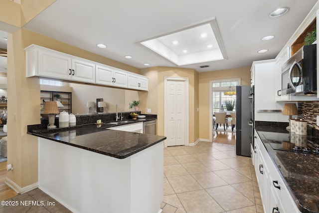 kitchen featuring a raised ceiling, sink, white cabinets, kitchen peninsula, and stainless steel appliances