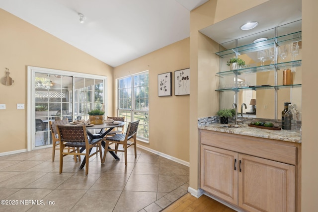 dining room featuring lofted ceiling, wet bar, and light tile patterned floors