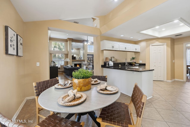 dining space featuring lofted ceiling, sink, and light tile patterned floors