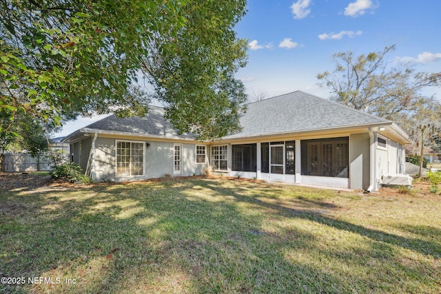 rear view of house featuring a sunroom and a lawn