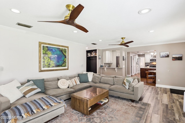 living room featuring crown molding, baseboards, ceiling fan, and wood finished floors