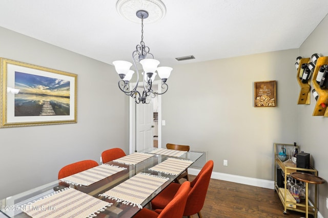 dining area featuring baseboards, visible vents, an inviting chandelier, and wood finished floors