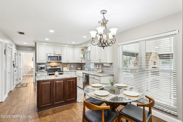 kitchen with stainless steel appliances, visible vents, white cabinets, decorative backsplash, and open shelves