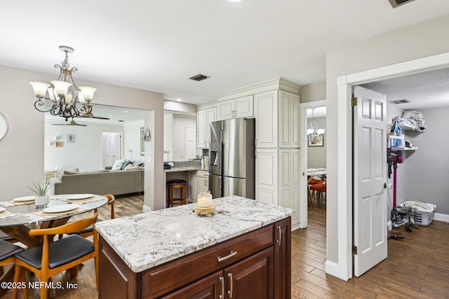 kitchen with visible vents, dark wood-type flooring, light stone countertops, a chandelier, and stainless steel refrigerator with ice dispenser