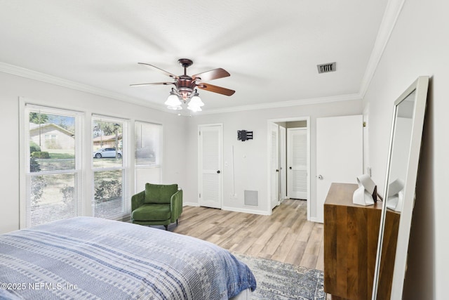 bedroom featuring light wood-style flooring, visible vents, baseboards, and ornamental molding