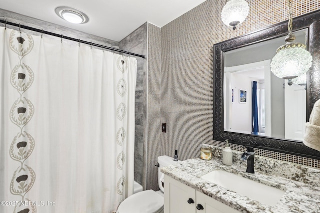 bathroom with tile walls, toilet, and vanity