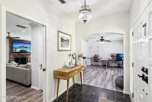 foyer featuring visible vents, arched walkways, dark wood-style flooring, and ceiling fan with notable chandelier