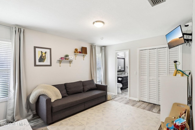 living area featuring visible vents, baseboards, and wood finished floors