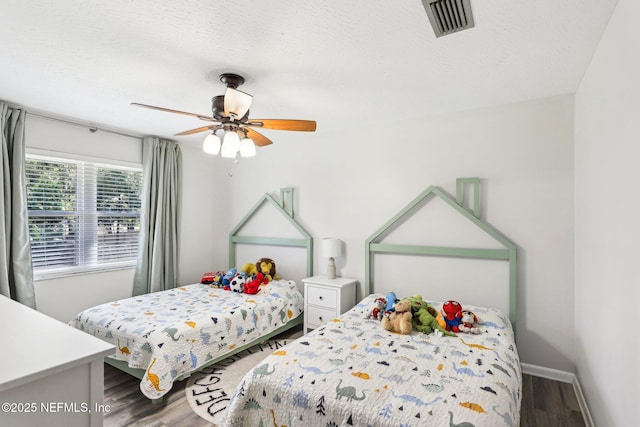 bedroom with a textured ceiling, visible vents, and wood finished floors