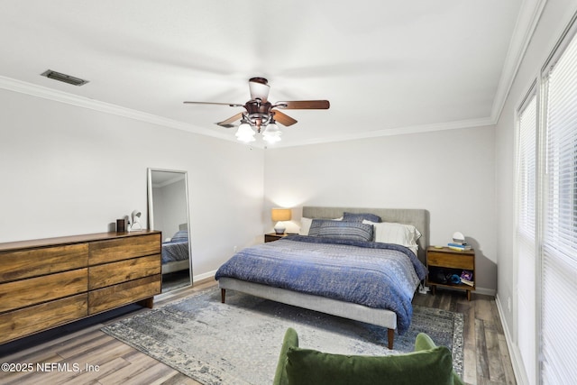 bedroom featuring baseboards, visible vents, wood finished floors, and ornamental molding