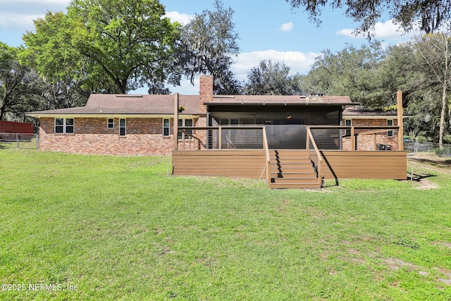 back of property featuring a yard, a chimney, fence, and a wooden deck