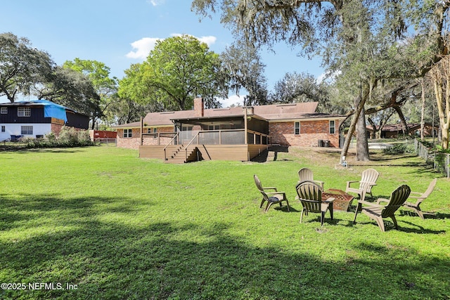 view of yard with a sunroom, an outdoor fire pit, and a wooden deck