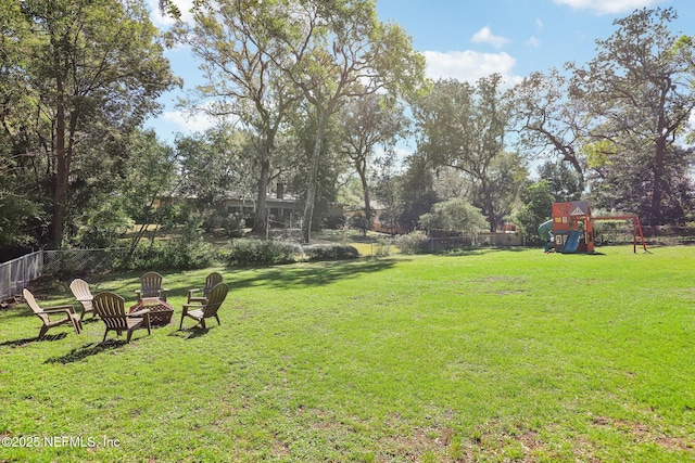 view of yard with an outdoor fire pit, a playground, and fence