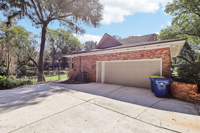 garage featuring concrete driveway and central AC