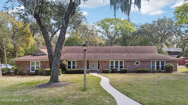 ranch-style home featuring brick siding and a front lawn