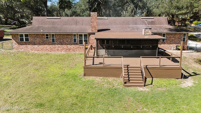 rear view of property with a deck, a sunroom, a yard, stairway, and a chimney