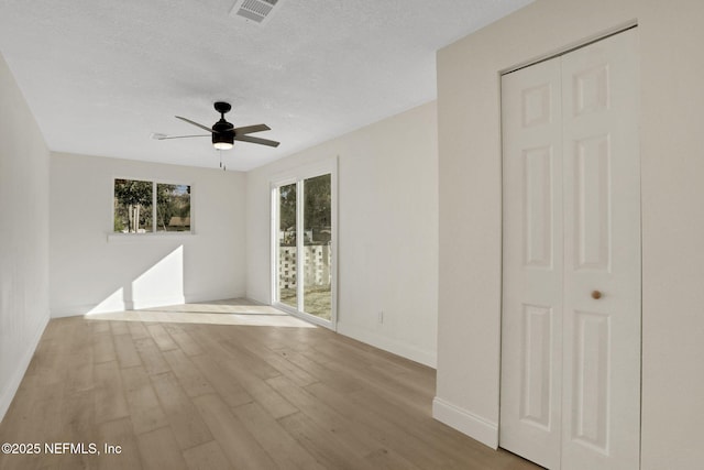 unfurnished room featuring ceiling fan, light hardwood / wood-style flooring, and a textured ceiling