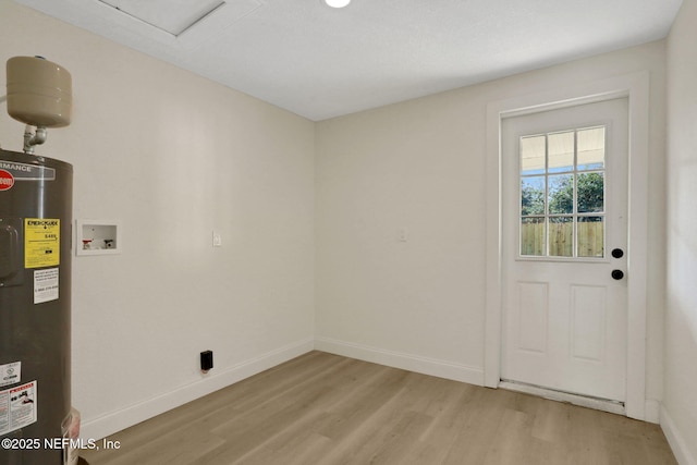 laundry area featuring washer hookup, electric water heater, and light hardwood / wood-style flooring