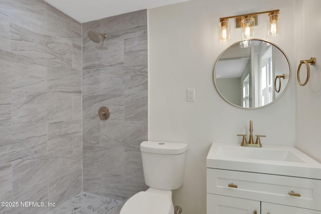 bathroom featuring vanity, toilet, and tiled shower