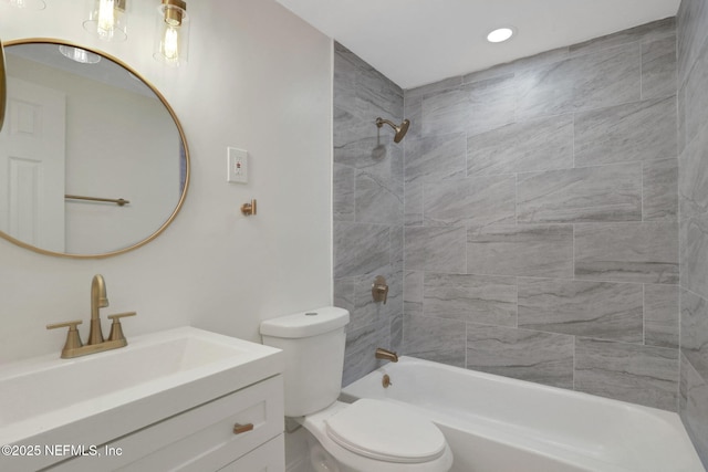 full bathroom featuring tiled shower / bath combo, vanity, and toilet