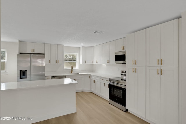 kitchen featuring white cabinetry, appliances with stainless steel finishes, sink, and light hardwood / wood-style floors