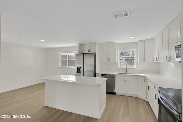 kitchen featuring sink, stainless steel appliances, white cabinets, and a kitchen island