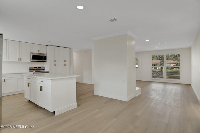 kitchen with stainless steel appliances, a center island, light wood-type flooring, and white cabinets