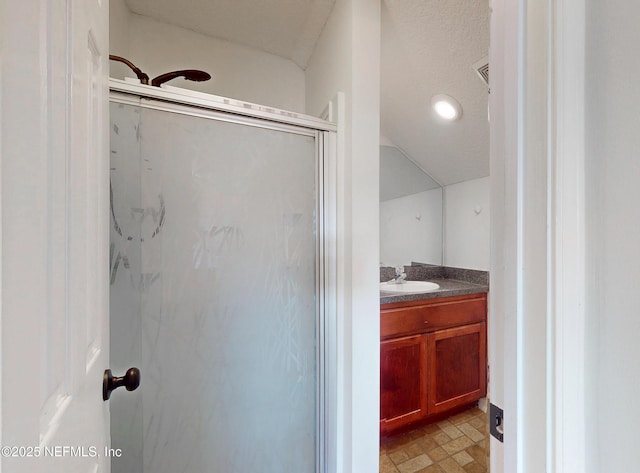 bathroom featuring vanity, a textured ceiling, and a shower with shower door