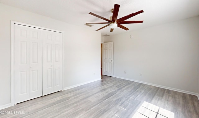 unfurnished bedroom with ceiling fan, a closet, and light wood-type flooring