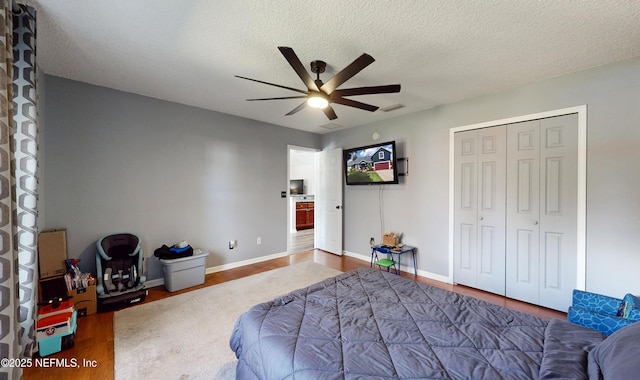 bedroom featuring ceiling fan, hardwood / wood-style floors, a textured ceiling, and a closet