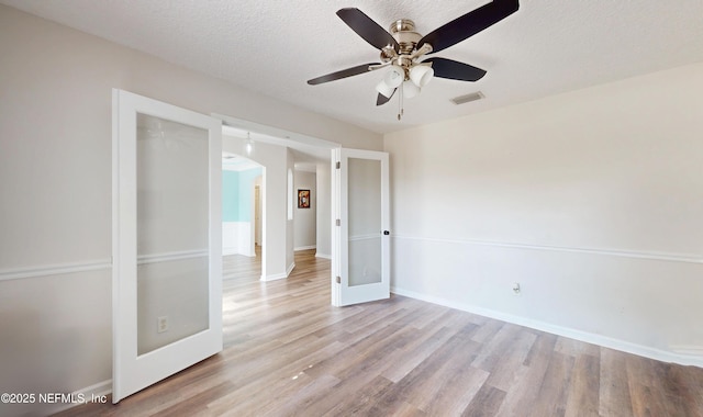 spare room with ceiling fan, a textured ceiling, and light hardwood / wood-style floors