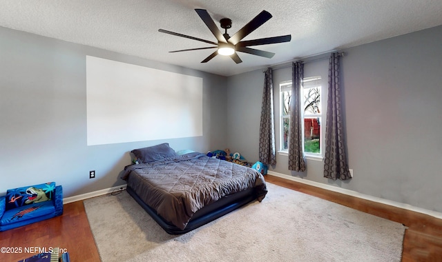 bedroom with ceiling fan, hardwood / wood-style flooring, and a textured ceiling