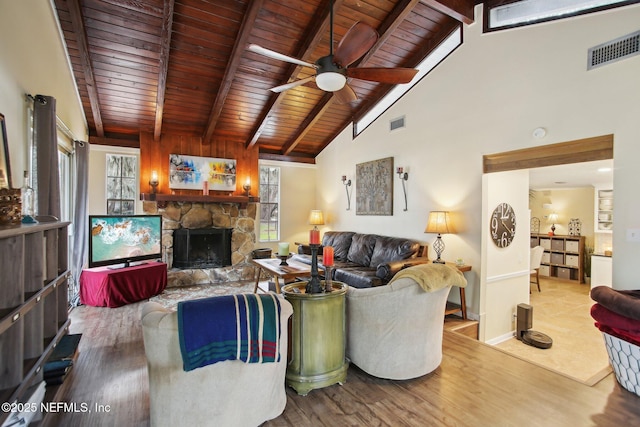 living room with a stone fireplace, wooden ceiling, beamed ceiling, and light wood-type flooring