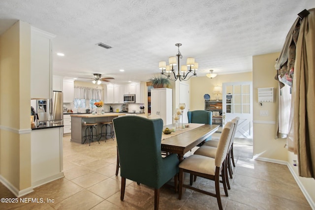 dining room with light tile patterned flooring, ceiling fan with notable chandelier, and a textured ceiling