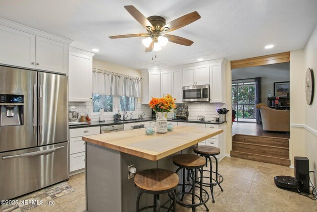 kitchen with appliances with stainless steel finishes, a breakfast bar, and white cabinets