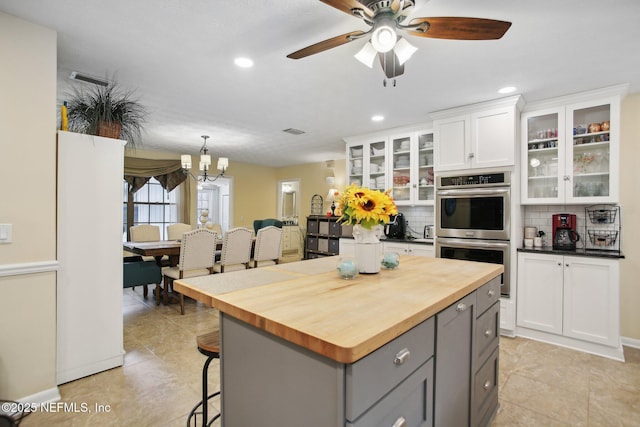 kitchen featuring gray cabinetry, double oven, backsplash, white cabinets, and wood counters